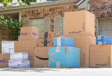 Amazon, FedEx, UPS, and U.S. Postal Services boxes stacked up in a homeowner's driveway.