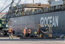 Images shows carg vessel and port workers.