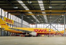Yellow DHL cargo jets inside a large hangar.