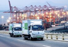 Images shows DB Schenker delivery trucks and container cranes.
